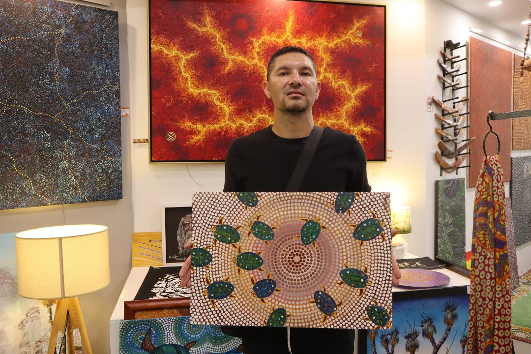 Jason Hapke holding Aboriginal Art of Turtles